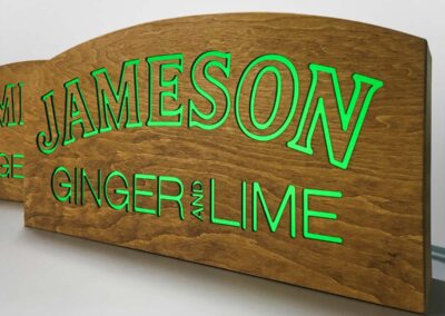 Fából készült, belülről átvilágított, zöldesen derengő Jameson logó és "Ginger and Lime" felirat.